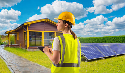 Woman builder. Solar panels on lawn. Country house. Electric station. Girl engineer adjusts solar panels. Photovoltaic generators. Woman near solar panels. Wooden house. Caring for environment