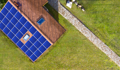 Solar panels on roof. Country cottage top view. Eco photovoltaic panels. Roof with solar...