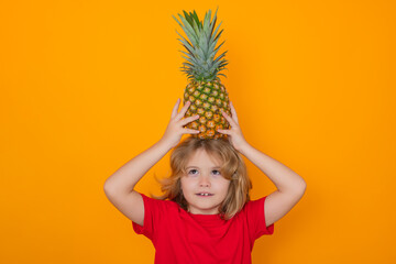 Kid with pineapple in studio. Studio portrait of cute child hold pineapple isolated on yellow background.
