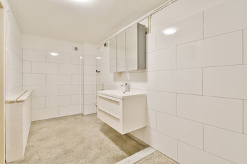a bathroom with white tiles on the walls, and an open door leading to a washer in the corner