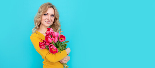 glad young woman with spring tulip flowers on blue background. womens day. Woman isolated face portrait, banner with mock up copy space.
