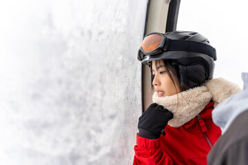 Young Asian woman rises to snow mountain peak on cable car cabin
practice snowboarding at ski...