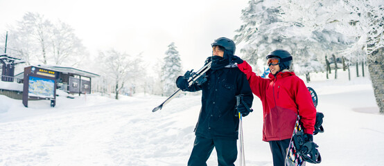 Asian man and woman practice freeriding snowboard and ski on snowy mountain at ski resort. People...