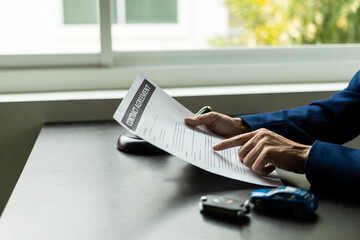 The car dealership office calculates the interest rate and the cost of a car loan. Providing financial and insurance services while the customer reads the terms and conditions of the contract