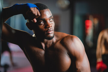 Obraz na płótnie Canvas Young muscular african american male boxer looking at camera, wearing boxing gloves, standing isolated over grey background. Sports, workout and bodybuilding concept, confident african american boxer