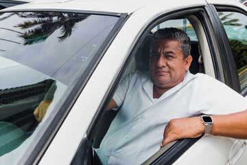 latin taxi driver senior man with car on background at city street in Mexico in Latin America,...