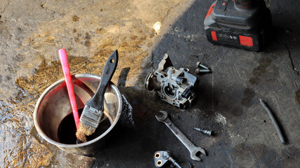 The local mechanic cleans the motorcycle carburetor with gasoline