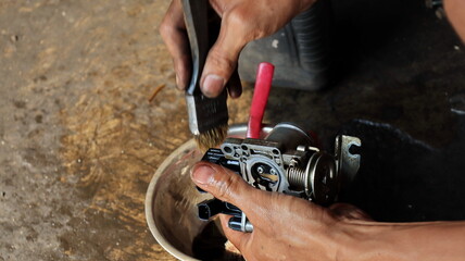 The local mechanic cleans the motorcycle carburetor with gasoline