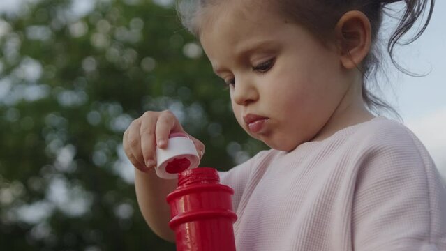 Child girl blowing soap bubbles, having fun playing outside at the sunset. Cute kid smiling, holiday in summer outdoor. Baby. Happy childhood concept