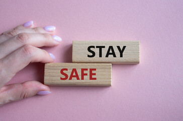 Stay Safe symbol. Concept word Stay Safe on wooden blocks. Businessman hand. Beautiful pink background. Business and Stay Safe concept. Copy space