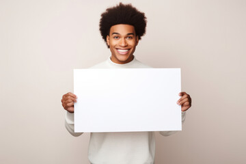 Happy young black man holding blank white banner sign, isolated studio portrait.