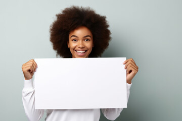 Happy young black woman holding blank white banner sign, isolated studio portrait.