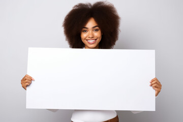 Happy young black woman holding blank white banner sign, isolated studio portrait.