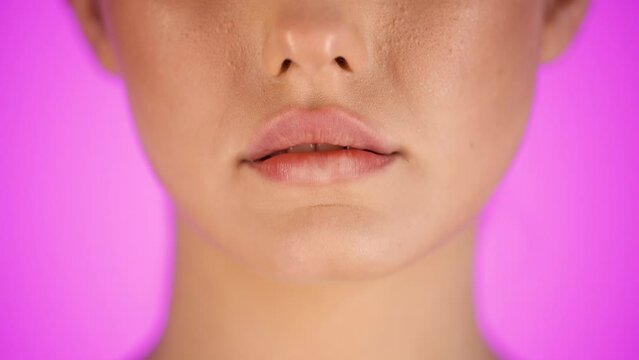 Caucasian woman bites her lower lip, close-up face, isolated purple background