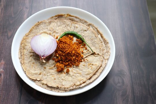 Jowar flour flatbread known as bhakar or jawari bhakri. served with spicy garlic or lasun chutney, green chilli and onion. farmer's food. Maharashtrian village food. copy space