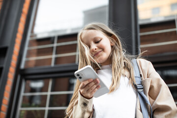 Fototapeta premium Back to school. A schoolgirl is looking for something on the smartphone screen