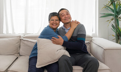 A sweet older couple enjoys quiet time together, seated comfortably on their vintage couch in a...