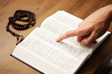 Naklejka premium Hands, person and reading bible with rosary cross for praying, spiritual faith and holy worship of God. Closeup of christian studying religion, gospel prayer books and learning praise to Jesus Christ