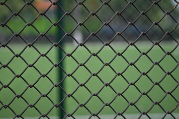 Fototapeta premium iron mesh close-up against the background of a green stadium