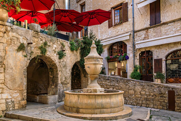 Traditional old stone fountain on a central square in the medieval town of Saint Paul de Vence,...