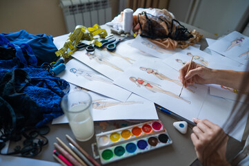 Woman drawing sketches of swimwear and underwear in watercolor. 