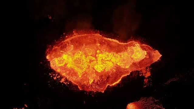 Aerial view above a lava outburst of a erupting Volcano crater - top down, drone shot