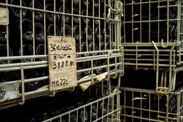 Black champagne bottles in metal cage in warehouse