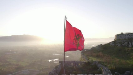Close up shot of albanian flag on top of Schloss Shkodra during sunrise, aerial
