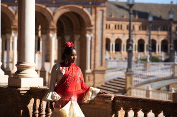 Young black woman dressed as a flamenco gypsy in a famous square in Seville, Spain. She wears a...