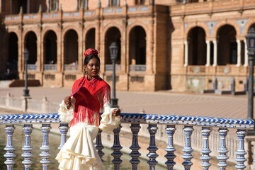 Young black woman dressed as a flamenco gypsy in a famous square in Seville, Spain. She wears a...