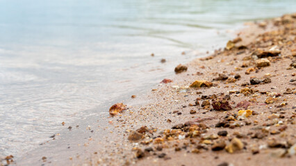 ฺAbstract of Beach lined with sand and a few rocks. Blurred image of waves crashing on the beach.