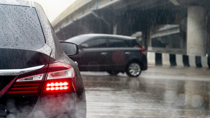 Rear side car black open red light of brake.  Scattered rain that blurs all around is not clear. Rainstorm on the road with different bridges on the sides.