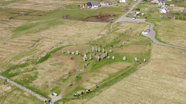 Medium close up drone shot of the Callanish Standing Stones on the Isle of Lewis, part of the Outer Hebrides of Scotland. Filmed on a sunny, summers day. Tourists and visitors are visible.