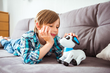 Happy teen boy playing takes care of dog robot