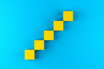 Fototapeta premium Blank yellow cube blocks arranged as step stairs ladder of success on blue background.