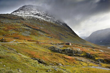 beautiful Norway landscape under cloudy sky with autumnal colors in mountain with a little chalet