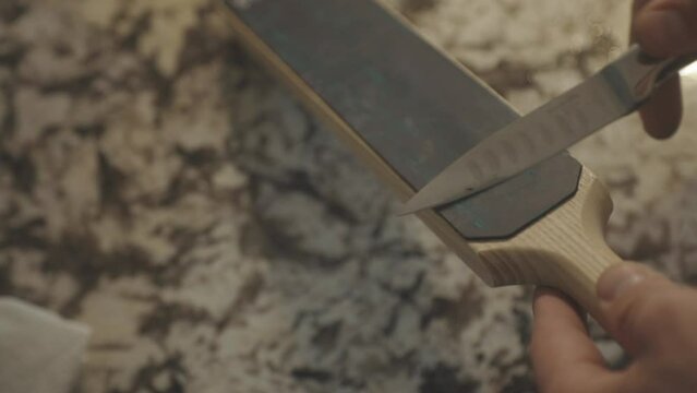 Sharpening Knife With Leather Strop Sharpener In The Kitchen. closeup