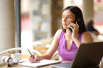 Student talking on phone in a restaurant terrace - obrazy, fototapety, plakaty