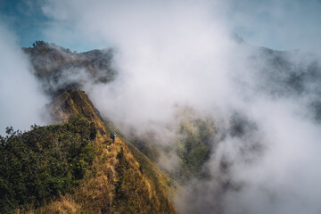 a person with blue backpack standing in the middle of mountain range and sea of cloud in northern of thailand (Nan province, Thailand) เด่นช้างนอน