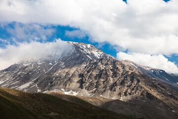 The snowy peak of the Tien Shan mountains covered with thick clouds