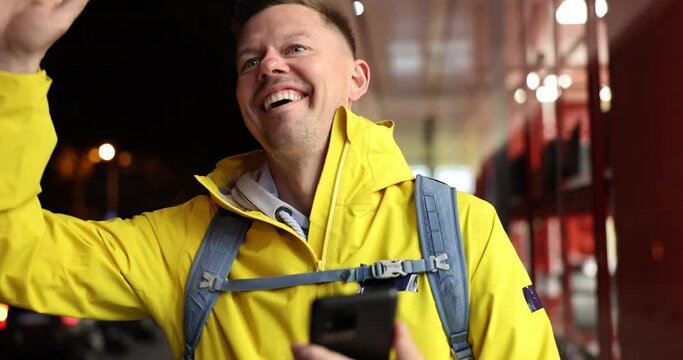 Male courier looking at mobile phone and waving to customer for food delivery 4k movie slow motion. City map in mobile apps concept