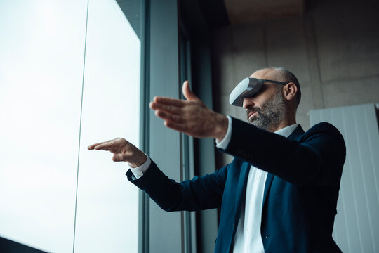 Mature businessman gesturing with virtual reality simulators in office