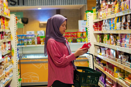 Happy mature Asian woman looking at product at grocery store. Costumer buying food at the market.