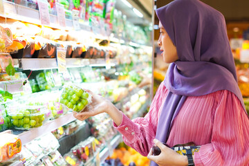 Happy mature Asian woman looking at product at grocery store. Costumer buying food at the market.