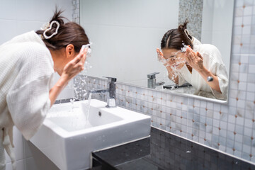 Asian beautiful woman washing her clean face with facial foam and water. 