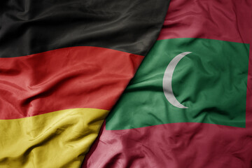 big waving realistic national colorful flag of germany and national flag of maldives .