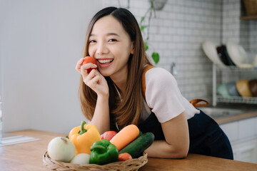 Woman is cooking in home kitchen. Female hands cut bell pepper, vegetables, greens, tomatoes on table on wooden boards. Healthy food, salad or vegetarian food.