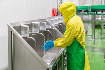 Worker washing hands with soap in food factory.