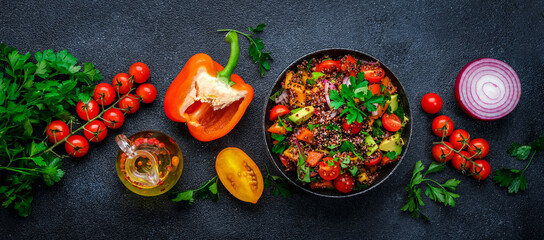 Tabbouleh salad with quinoa and cherry  tomatoes, red paprika, avocado, cucumbers, onion, parsley. Middle Eastern and Arabic dish. Black table background, top view