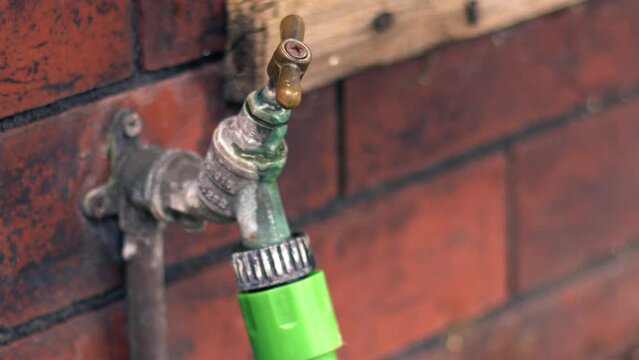 Rickety leaking outside faucet tap in a garden close up shot